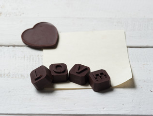 Fototapeta na wymiar Chocolate Love with note paper on the wooden background