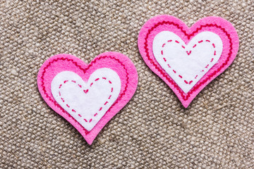 Two fiber heart shapes on linen fabric.