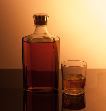 Glass and bottle with ice cubes and reflection drink alcohol on
