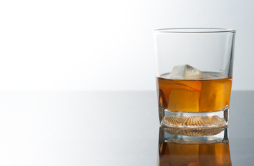 whiskey glass with ice cubes and reflection drink alcohol on gre