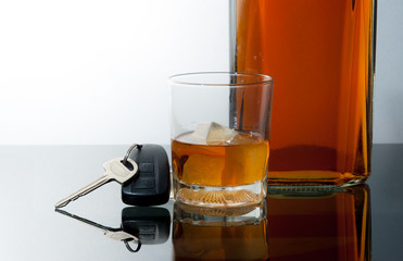 Glass of whiskey and car keys on gradient background