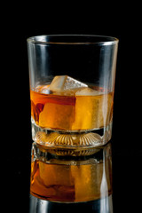 glass with whiskey against a black background
