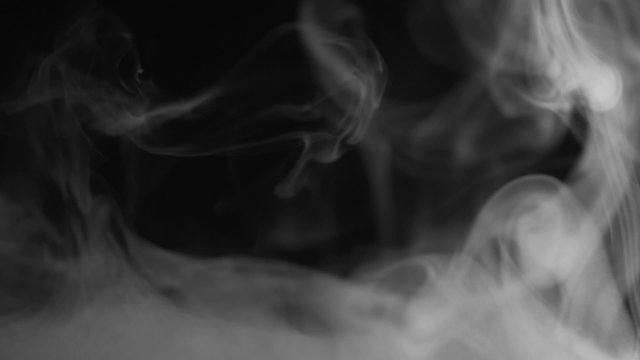 Real white steam looking like smoke isolated on black background. Clouds of white fantasy smoke abstract magic mystic fog toxic gas fumes pollution. Slow motion. Camera locked down. Recorded in 60fps