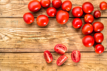 Fototapeta na wymiar Cherry tomatoes on wood background with copy space, top view.