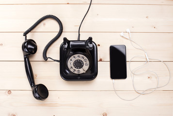 Old retro black phone and new cell phone on wooden board, top view, DOF, focus on phone