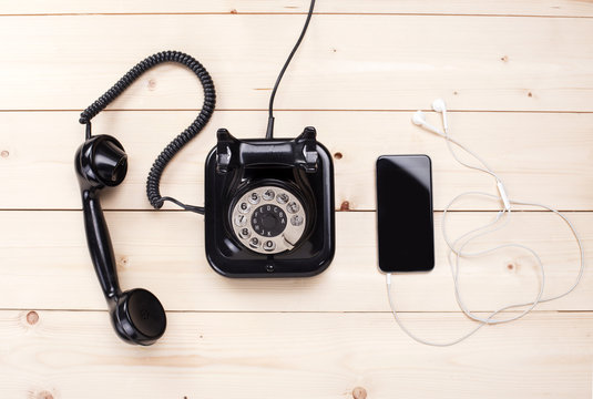 Old retro black phone and new cell phone on wooden board, top view, DOF, focus on phone