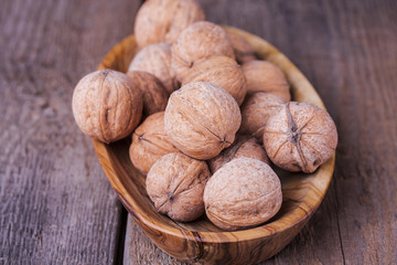 Pile of walnuts the shell on a wooden background