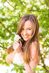 Beautiful happy young woman in the spring garden among apple blossom, soft focus