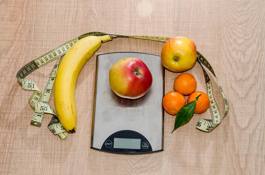 Concept of diet. Low-calorie fruit over measuring weight