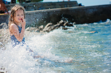 Obraz premium happy child girl in swinsuit relaxing on the beach and playing with water. Summer vacation at sea.