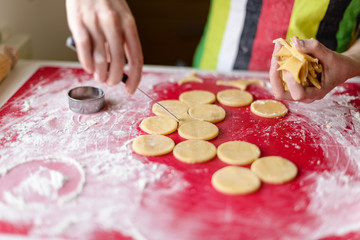 close up of female hands making cookies from fresh dough at home