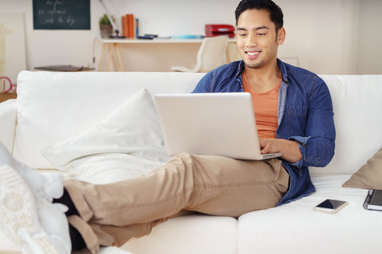 student sitzt auf dem sofa und schaut auf sein notebook