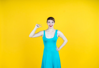 It is too small. Colorful studio portrait of pretty young woman showing small size with her fingers.  Yellow background.