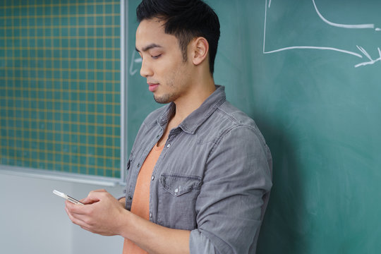 student im kursraum schaut auf sein handy