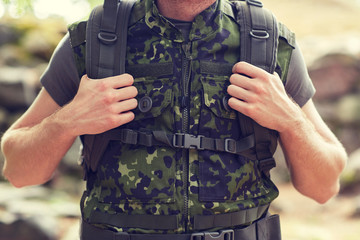 close up of young soldier with backpack in forest