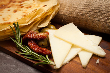 Traditional Sardinian flat breads served with cheese, olives and sundried tomato. - obrazy, fototapety, plakaty