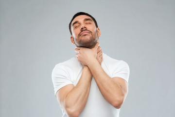 young man choking himself over gray background