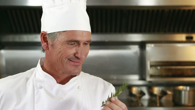 Handsome chef smelling rosemary and doing ok sign