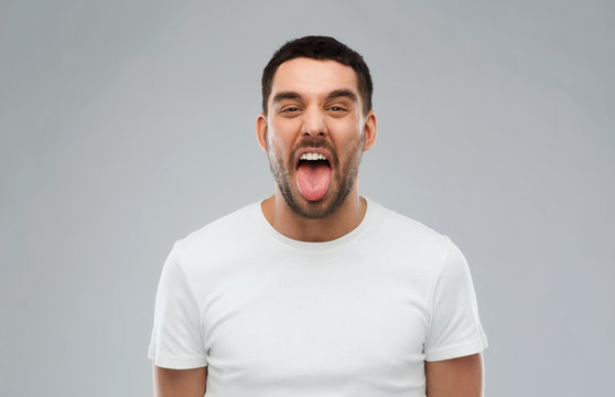 man showing his tongue over gray background