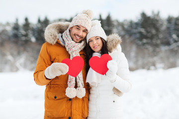 happy couple with red hearts over winter landscape