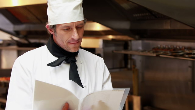 Handsome chef reading recipes