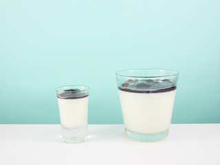 The tasty homemade blueberry panna cotta (Italian pudding dessert) in the small glass on white...