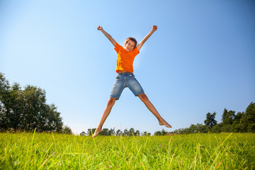 Fototapeta na wymiar Kid jumping on the sunny meadow outdoors