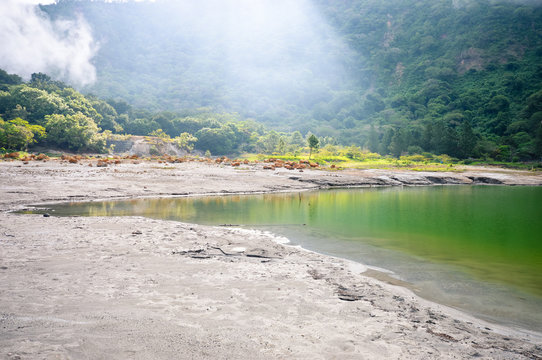 Rays of sunlight cover the the crater of Tecapa volcano through the cloud, near the town of Alegria in El Salvador. Sulphur lake on the foreground, rocks and crater wall - on the background
