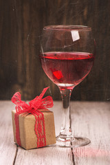 Gift box and glass of rose wine. Old vintage scrathed photo effect. Selective focus