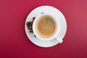 Coffee cup and beans on a red background