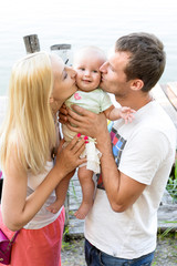Happy young family spending time outdoors on a summer day with blue sky in background. Spending time together having fun and smiling. Parents and their child. 