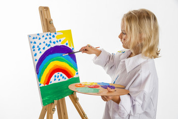 Little girl in a white robe painted a rainbow