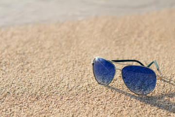 Fototapeta na wymiar Blue sunglasses on the beach