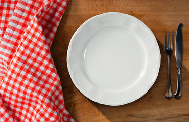 White Plate and Cutlery - Table and Tablecloth / Empty white plate on a wooden table with silver...