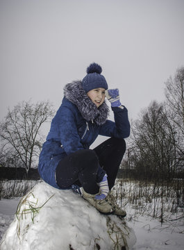 girl sitting on a big lump of snow
