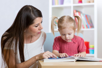 Fototapeta premium kid girl and mother read a book indoors