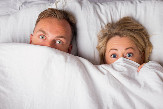 Man and woman hiding under blanket 