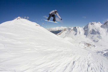 Flying snowboarder on mountains. Extreme sport.