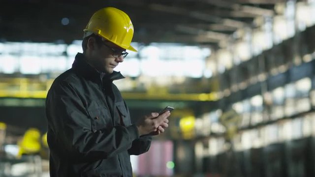 Technician in Hard Hat in using Phone in Industrial Environment. Shot on RED Cinema Camera.
