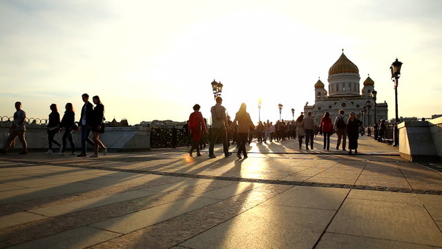 View of Cathedral of Christ the Savior and Patriarshiy bridge at sunset. Silhouettes of walking people. Moscow, Russia.