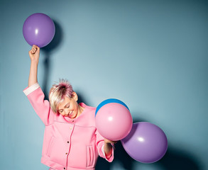 girl have fun with colored balloons on blue background