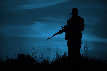 Fototapeta na wymiar Silhouette of military sniper with weapons at night.