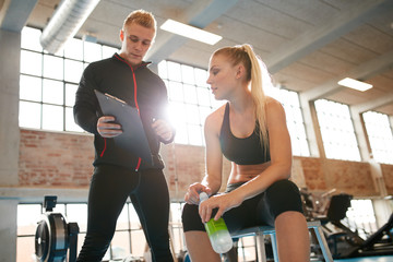 Personal trainer making an exercise plan for young woman