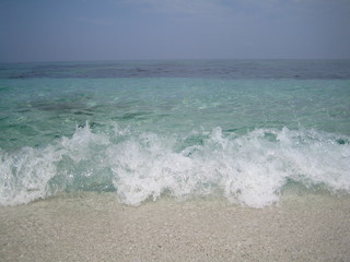 crashing blue waves on sardinian quartz sand