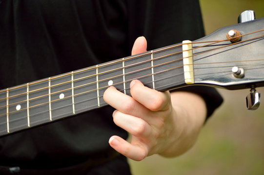 Closeup of guitar neck with guitarist playing