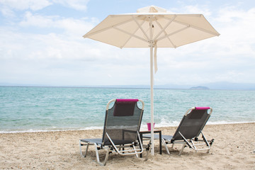 Blue sea and white sand beach with beach chairs and umbrella, Gr
