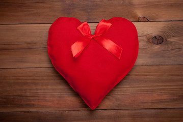 Red heart with a bow on a wooden background.