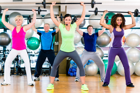 Männer und Frauen heben Langhantel im Fitnessstudio