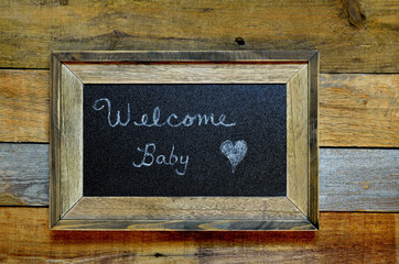 Welcome baby announcement on framed blackboard.  Conceptual congratulatory welcome of a newborn.