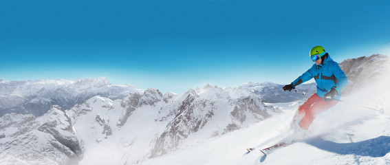 Naklejka na ściany i meble Man skier running downhill on sunny alpine slope